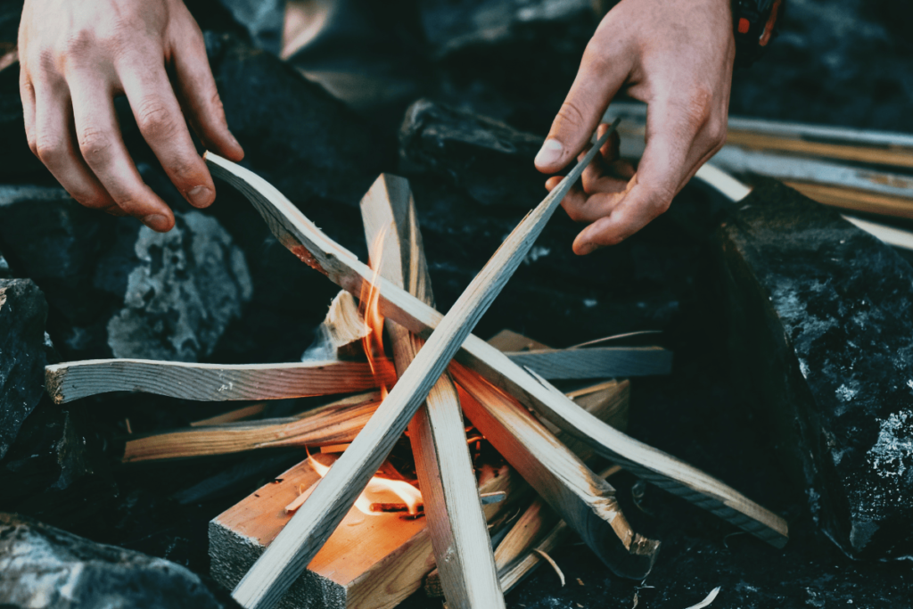 a photo of a bushcrafter starting a fire in a rock fire ring